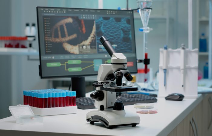 Scientific microscope on laboratory desk with researching instruments at professional workplace. Close up of investigation tool with glass lens for chemical substance lab examination